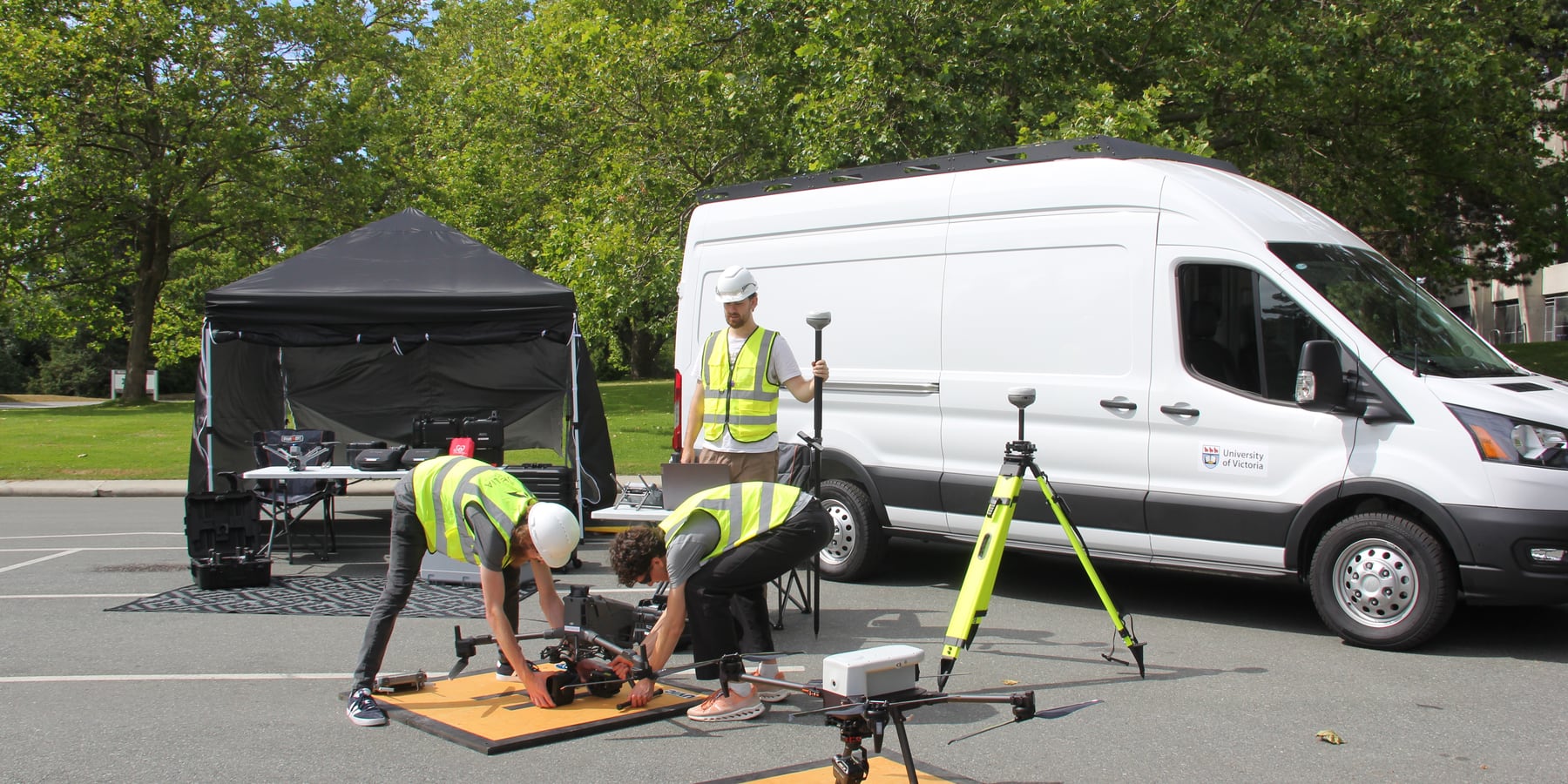 ACIS field team setting up drone and surveying equipment beside a University of Victoria vehicle.